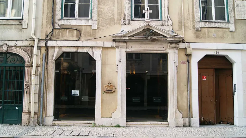 Portal da Igreja de Nossa Senhora da Oliveira;  Um frontão triangular, encimado por uma cruz, que encerra um ramo de oliveira em bronze, marca o portal da Igreja de Nossa Senhora da Oliveira