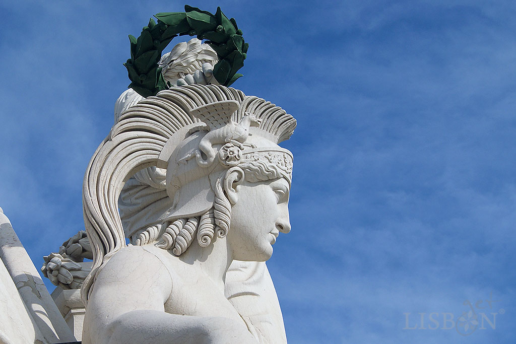 The female figure of the goddess Minerva wearing a plume helmet and holding a sword, with a lion resting by her side. On the two sides of the helmet are presented two small winged dragons, which remind us of the symbol of the House of Aviz.