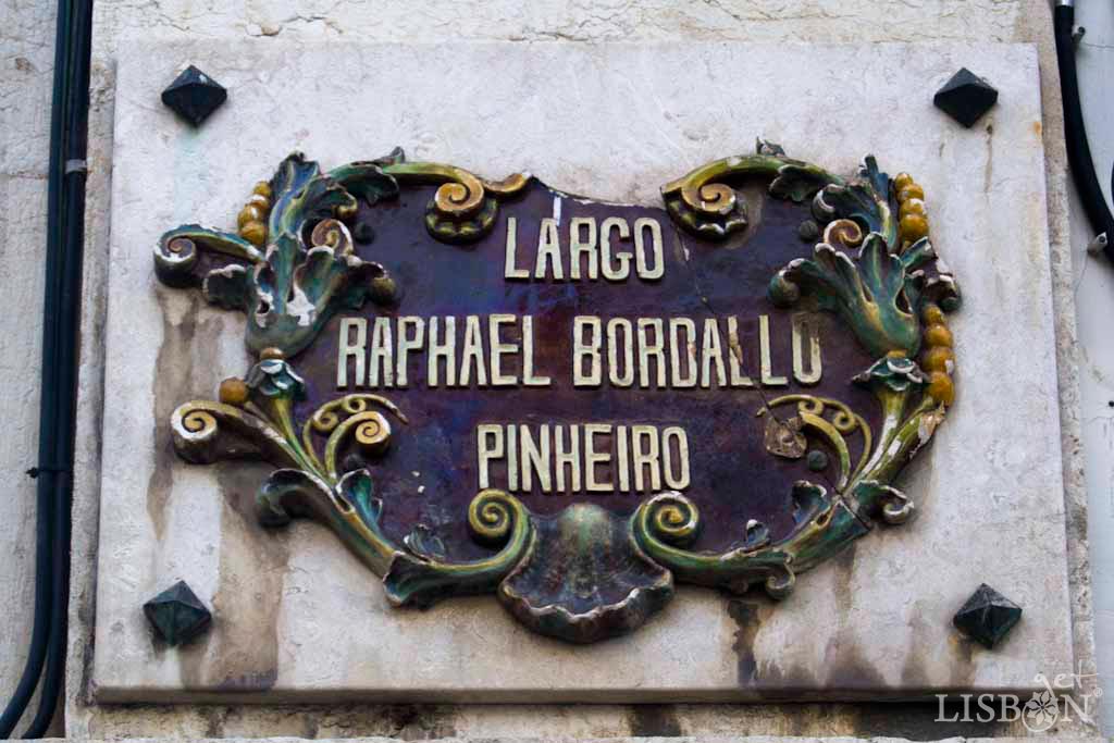 Placa toponímica do Largo Rafael Bordalo Pinheiro. As placas toponímicas em cerâmica, ali presentes, remetem para o seu trabalho como criativo ceramista que viveu e morreu no nº29, deste antigo Largo da Abegoaria.