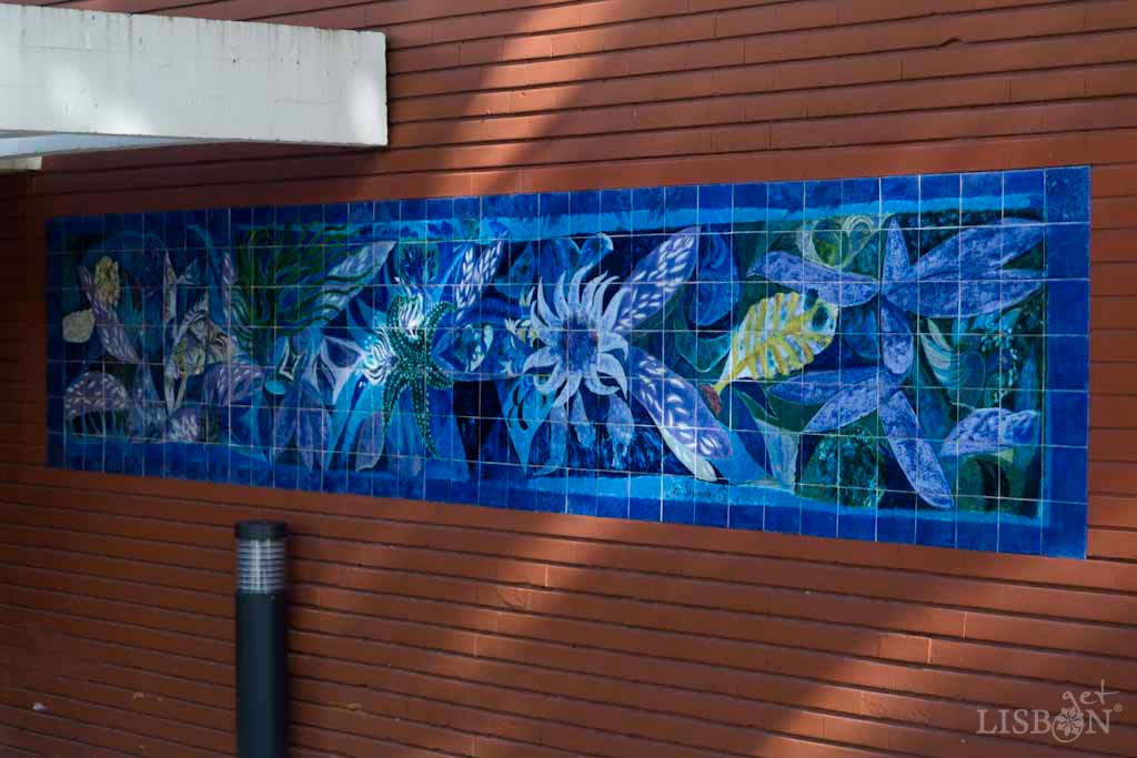 Tile panel by João Lopes Segurado. This is a composition formed by floral and plant elements, predominantly in tones of blue. It has 5,04m of length and 0,98m of height and is made of 252 tiles.