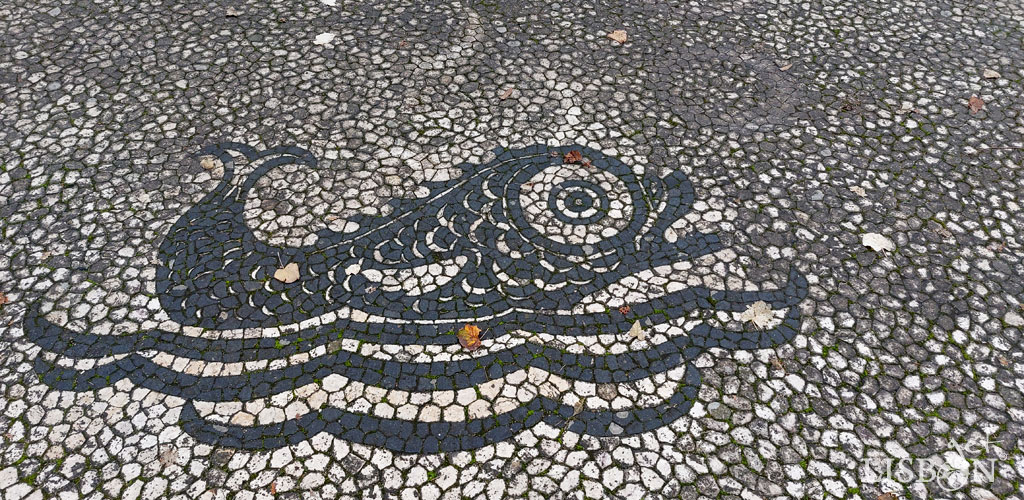 Animais e seres fantásticos na calçada portuguesa: três peixes sobre traços ondulantes na calçada que rodeia o monumento a Pedro Álvares Cabral